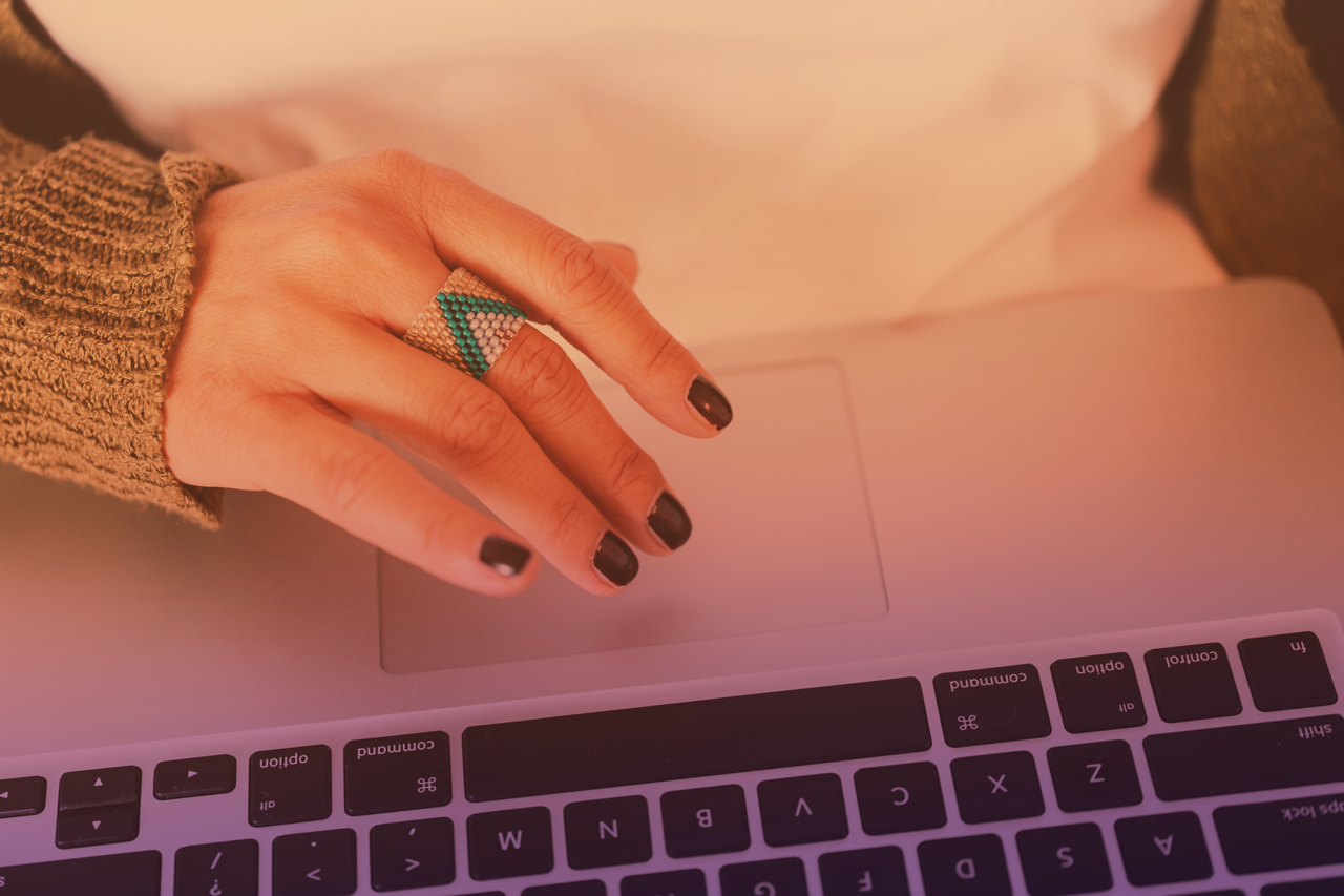 A woman's hand hovering over a laptop touchpad